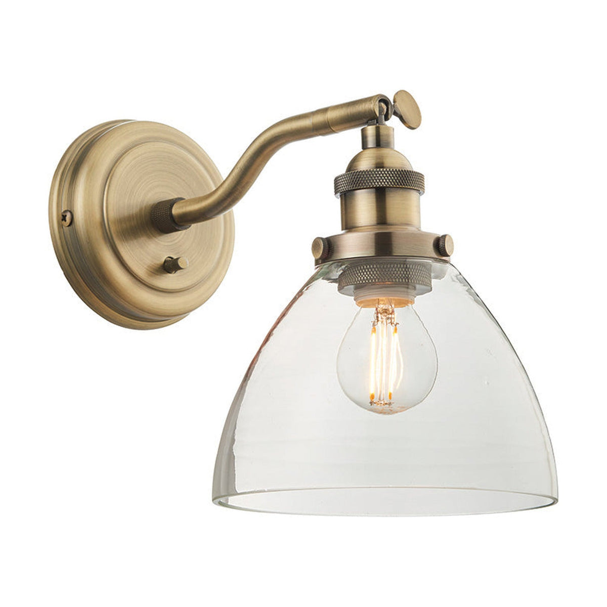 Wentworth Wall Light in brass with adjustable knuckle arm, knurled lamp holder, clear dome glass shade and exposed bulb, shown on a plain white background.