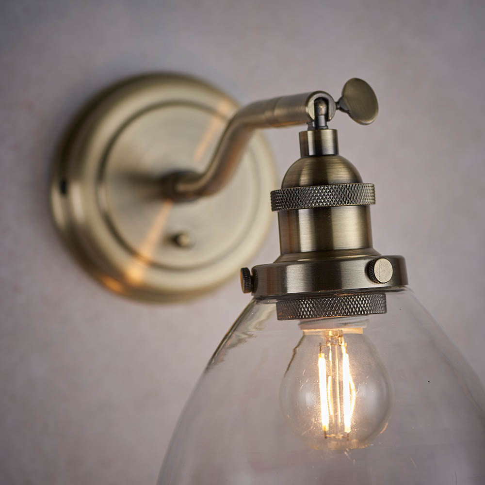 Wentworth Wall Light in brass, showing the adjustable knuckle joint, knurled lamp holder and clear glass shade with visible bulb against a light background.