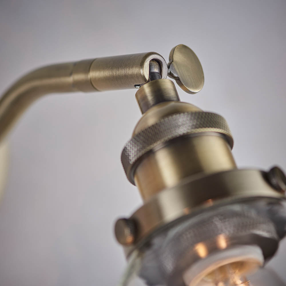 Close-up of the brass Wentworth Wall Light showing the adjustable knuckle joint, knurled lamp holder, and clear glass shade.