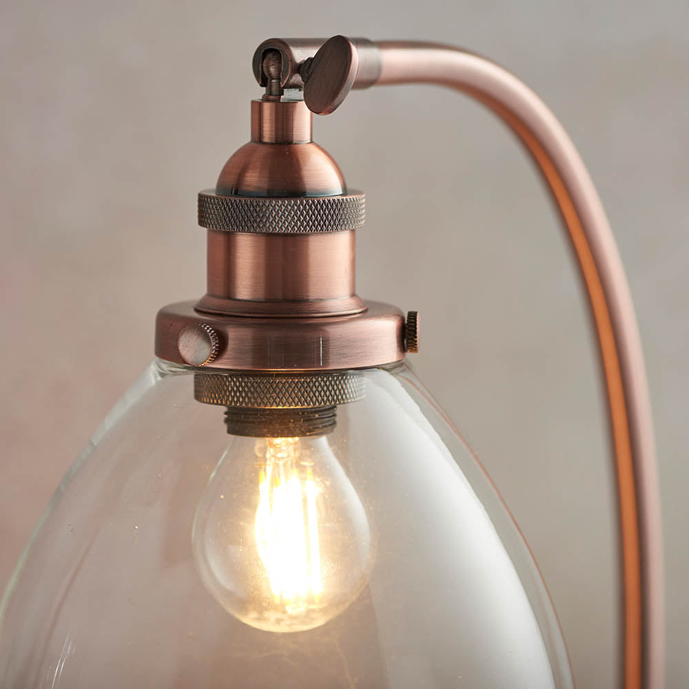 Endon Wentworth table lamp close-up showing copper knurled lamp holder, adjustable knuckle, clear glass shade and lit E14 filament bulb.