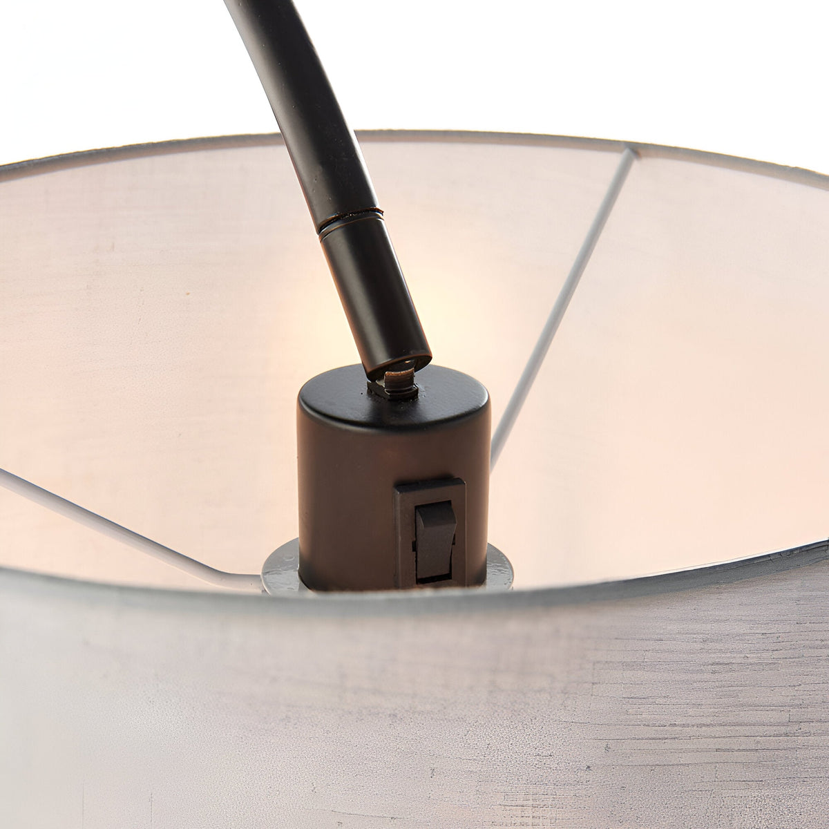 Close-up of the Endon Bevbourne floor lamp's matt black lamp holder with rocker switch, tilting arm, and light grey fabric shade interior.