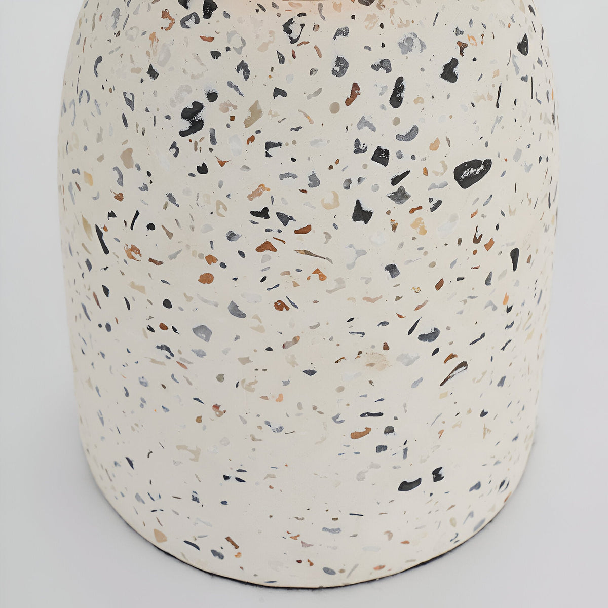 Close-up of the Endon Crangrove table lamp's white terrazzo base, showing matt speckled composite with black, grey and warm brown aggregate flecks.
