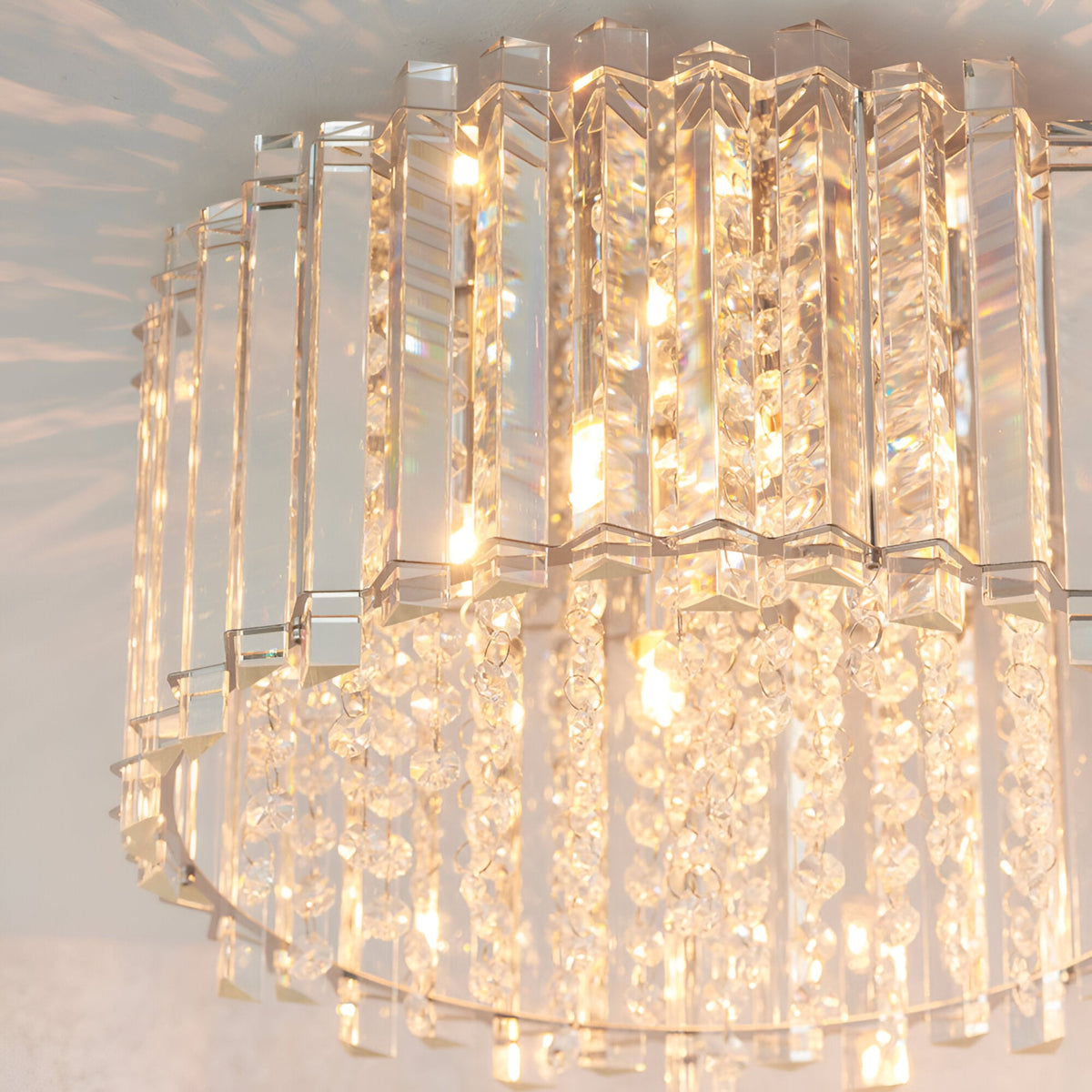 Close-up of the Brenbourne flush ceiling light showing tiered clear crystal rods and faceted glass droplets on a polished chrome frame, illuminated.