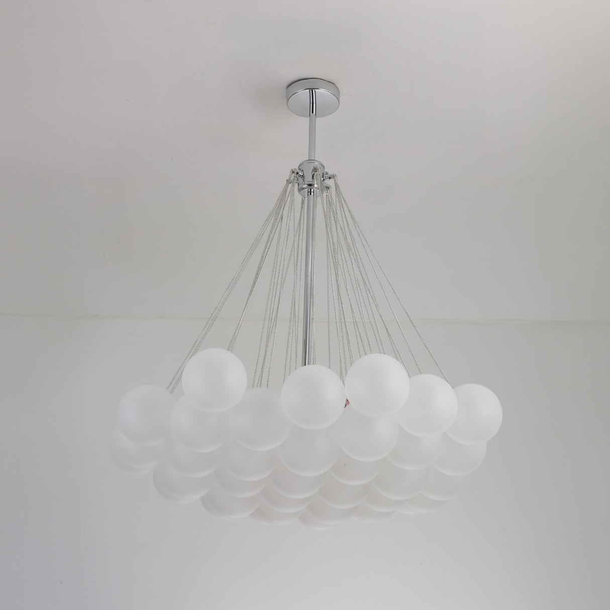 The Orb 37 Light Cluster Suspension - Silver features frosted glass spheres in a grid, suspended by sleek metal cables from a central chrome fixture for a modern, elegant ceiling statement.