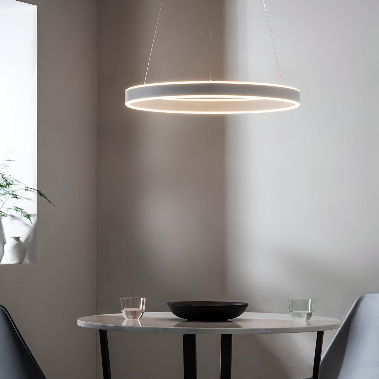 Bramford Pendant in matt nickel and white, a slim ring-shaped LED fixture suspended on thin cables above a marble dining table in a neutral room.