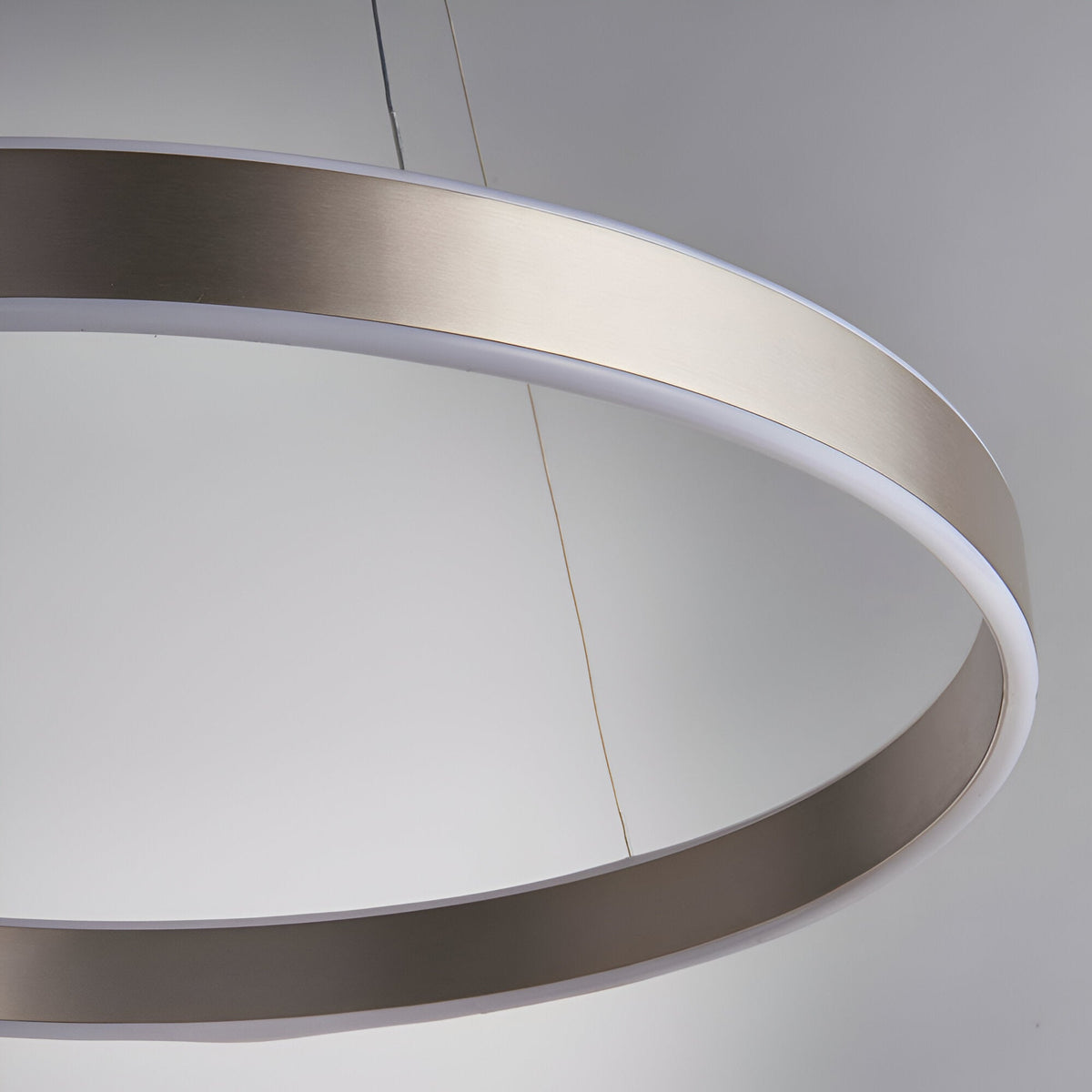 Close-up of the Bramford Pendant ring light in brushed nickel with a white frosted diffuser edge, suspended on a thin cable against a plain grey background.