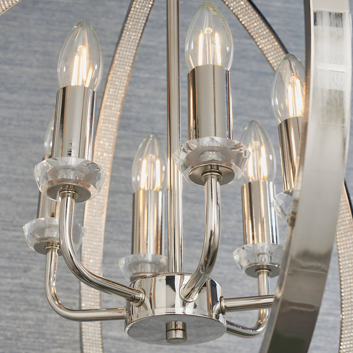 Cliffbury 6 Light Pendant in polished nickel, close-up of candle-style bulbs on curved arms with faceted crystal details against a mirrored frame.