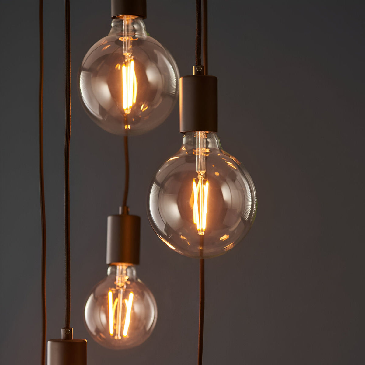 Marlowe 6 Light Pendant in matt black, showing globe bulbs on staggered black fabric flex drops against a dark background.