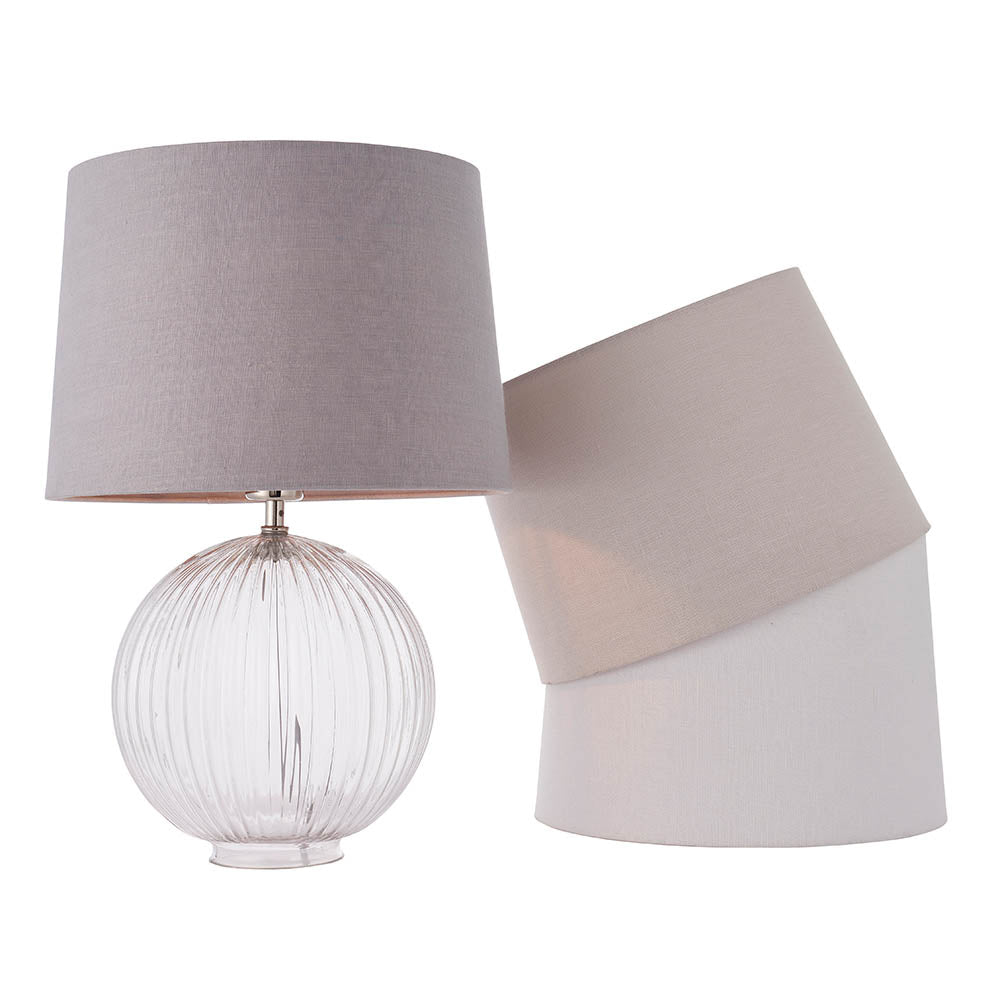 Endon Brockdale table lamp with clear ribbed glass base and satin nickel detailing, shown with grey, taupe and white fabric shade options on a white background.
