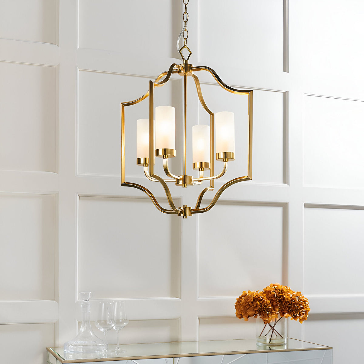 Endon Brackford 4 light pendant in satin brass with frosted glass cylinder shades, hung above a mirrored console with dried hydrangeas.