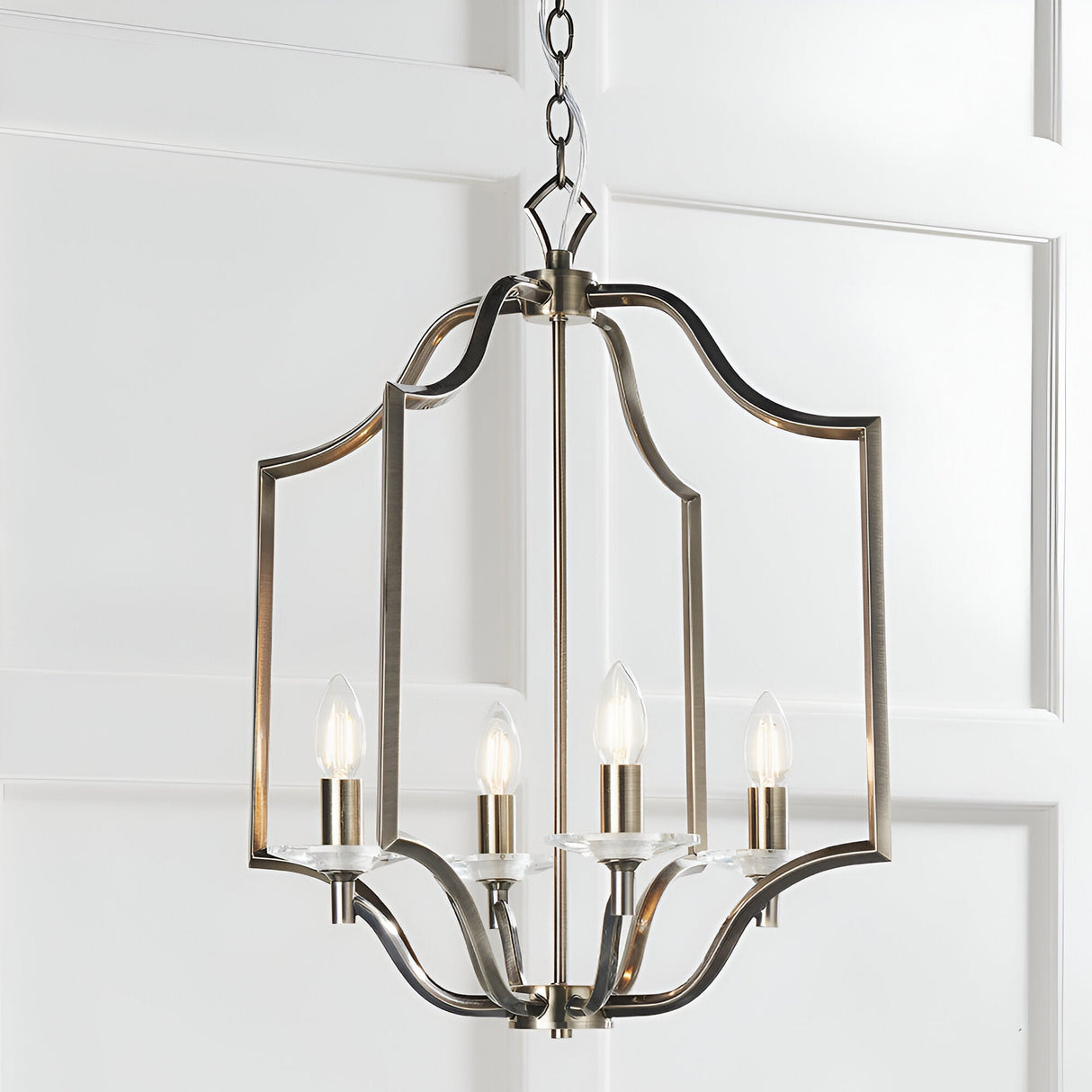 Endon Caldbourne 4 light pendant in antique brass with a curved open lantern frame, four E14 candle bulbs and clear crystal bobeches, chain suspended.