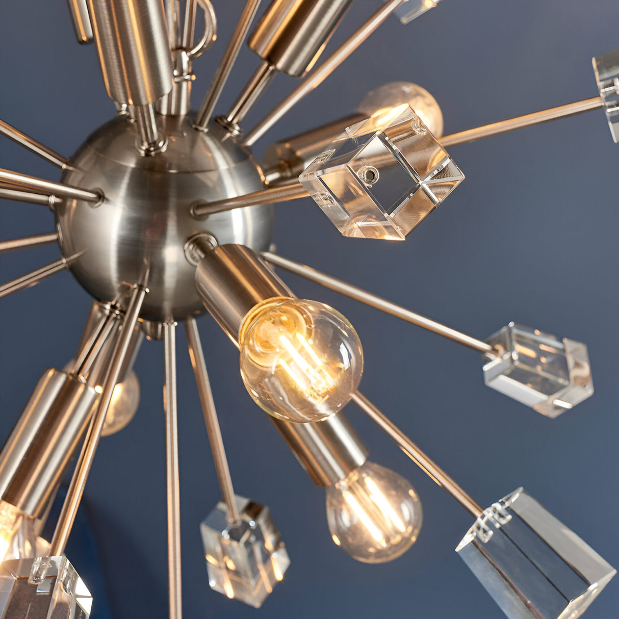 Carlgrove 9 Light Pendant in satin nickel, close-up of radiating rods with clear crystal glass cubes and exposed bulbs against a dark blue background.