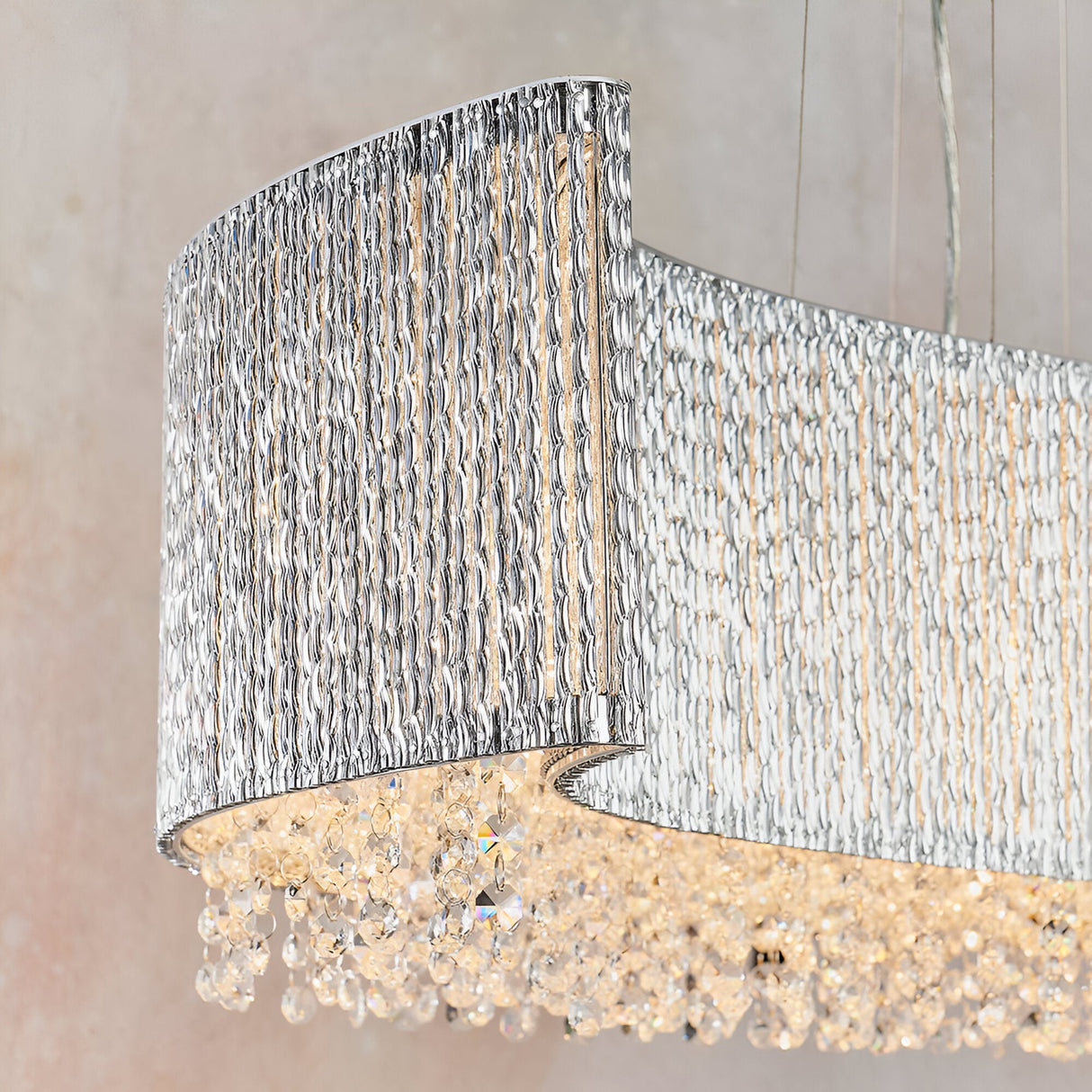 Close-up of the Endon Isadora linear pendant showing its twisted polished chrome rods forming a curved wave with clear crystal droplets below.