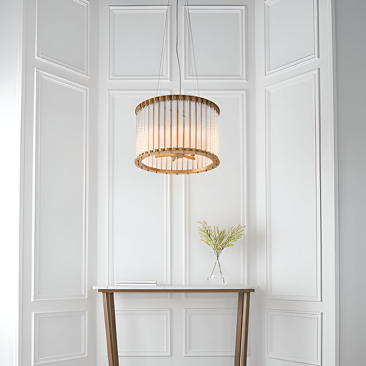 Cliffdale 6 Light Pendant in matt gold, drum-shaped frame with twisted glass rods, hanging above a console table against white panelled wall.