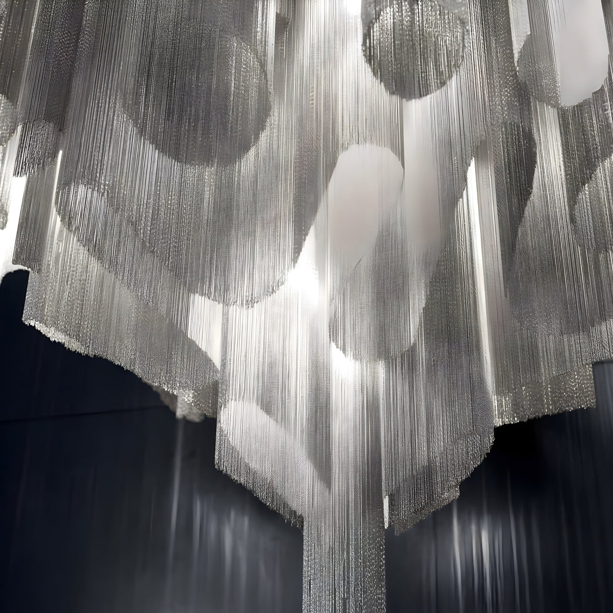 Close-up of Niori's Valora 15 Light Chain Veil Chandelier in nickel, showing layered silver metal chains draping around illuminated G9 lamps.