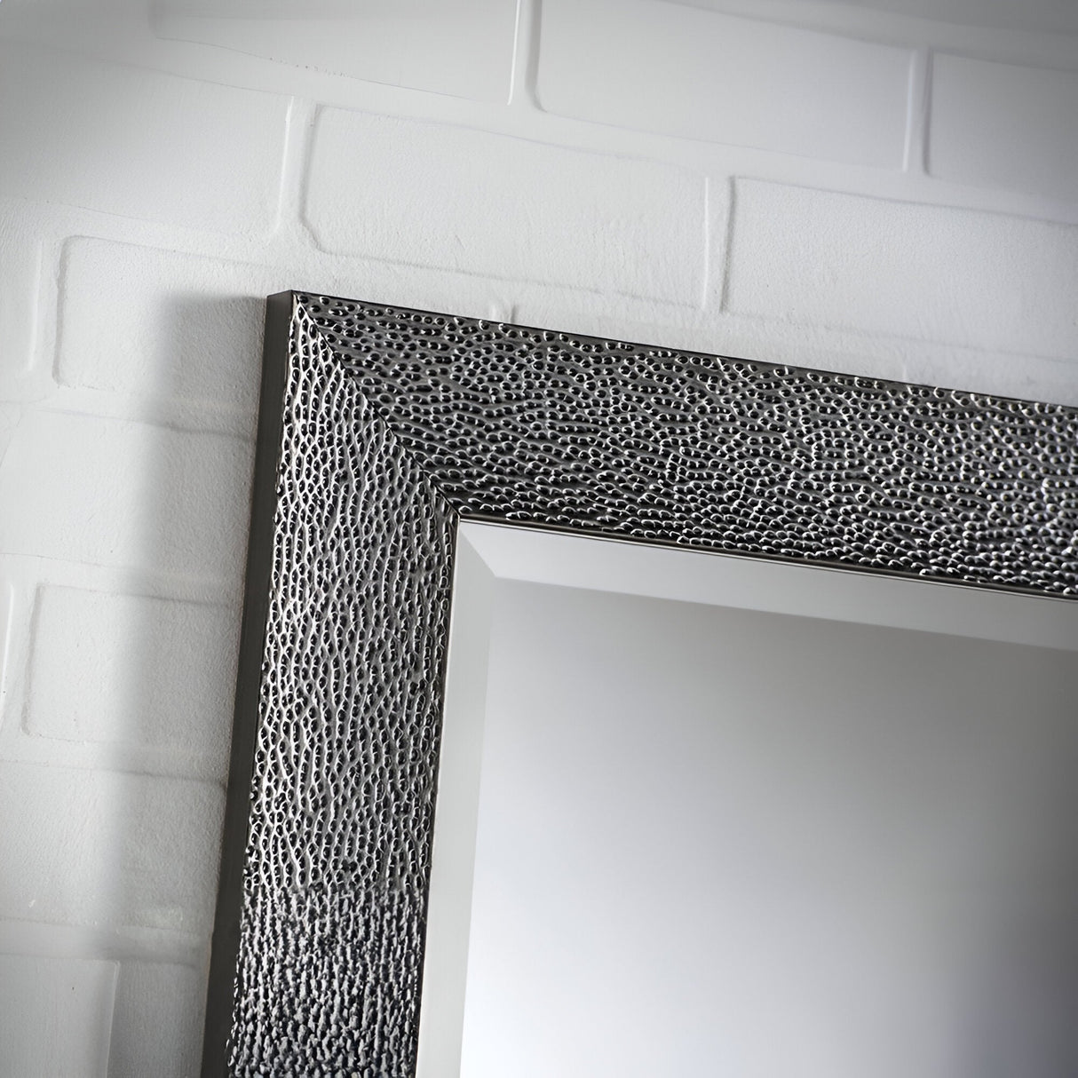 A detailed view of the Eclipso Rectangle Wall Mirror - Grey, highlighting its textured grey frame that radiates modern elegance, set against a white brick wall.