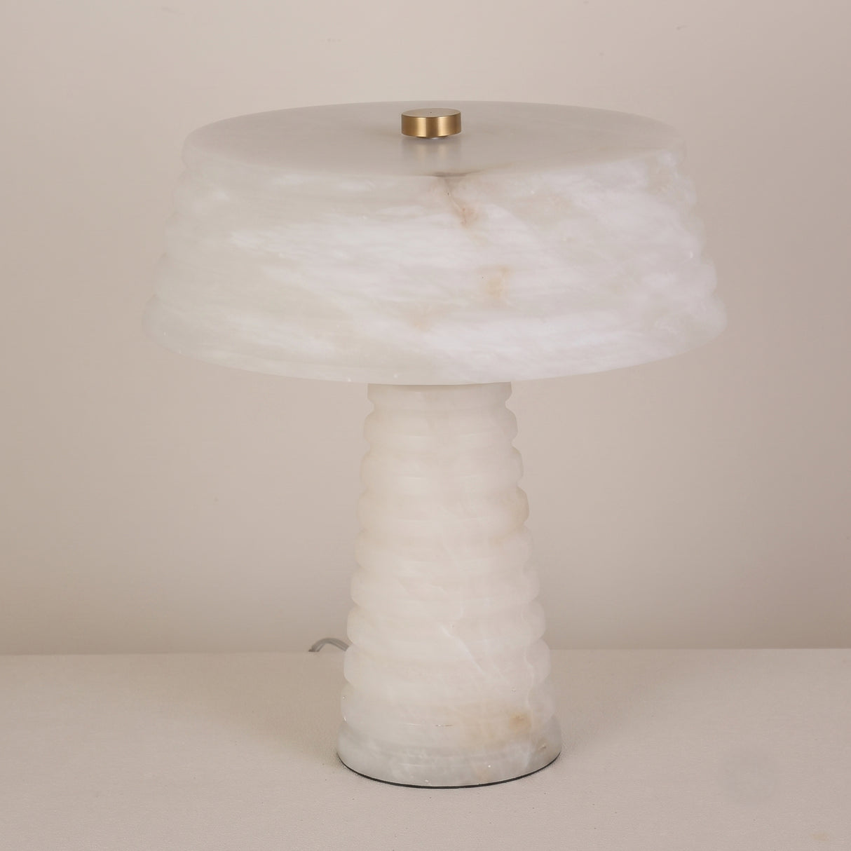 Orivon 3 Light Sculpted Alabaster Table Lamp in soft white, with a ribbed tapered base and banded drum-form shade joined by a brass finial, shown on a plain light background.
