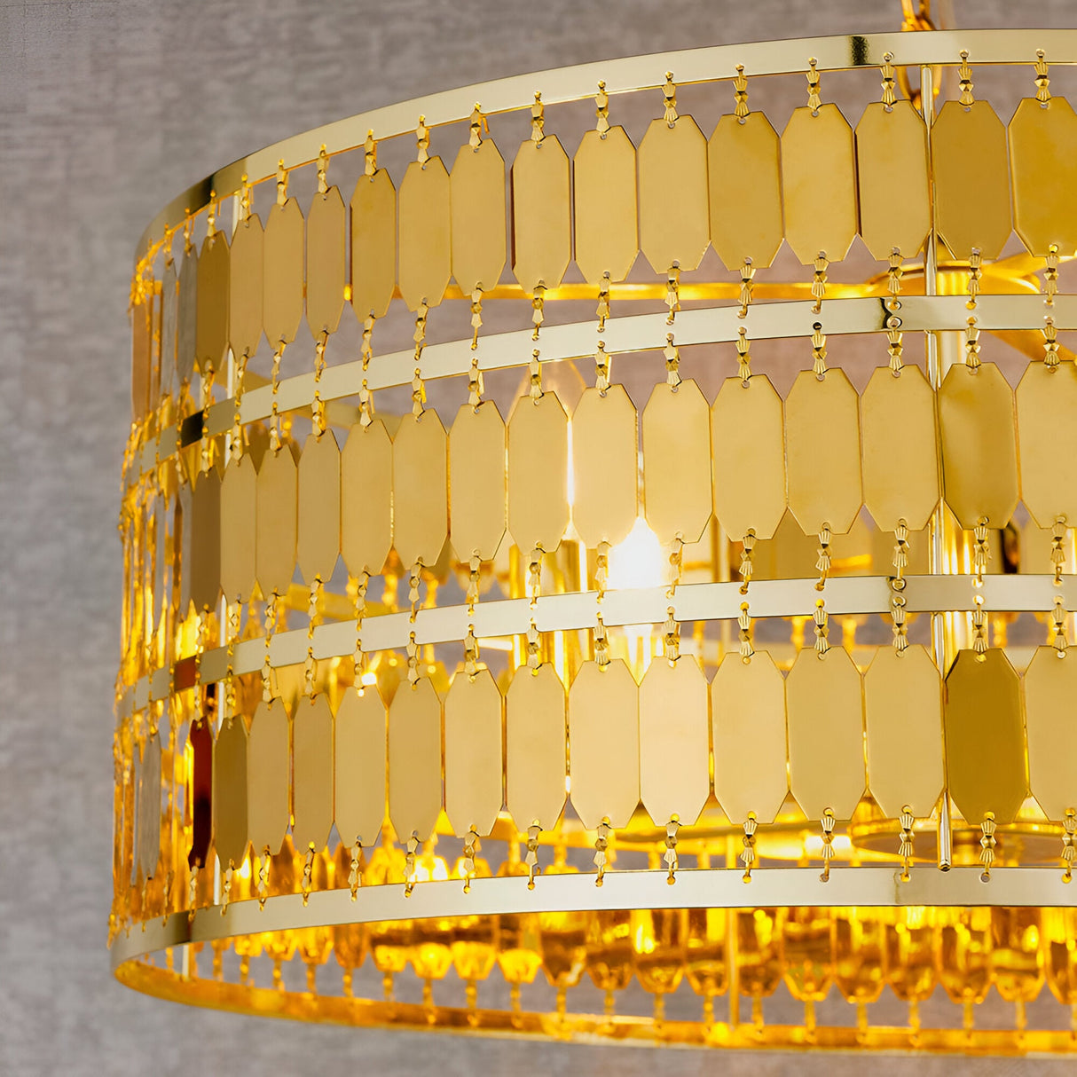Brackhurst 5 Light Pendant in gold, close-up of tiered hexagonal metal plates cascading around the drum frame, glowing bulb visible within.