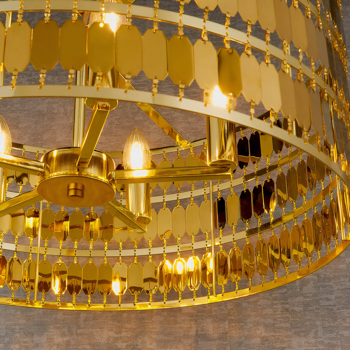 Close-up of the Brackhurst 5 Light Pendant in gold, showing layered hexagonal metal plates and candle-style bulbs on a central gold frame.