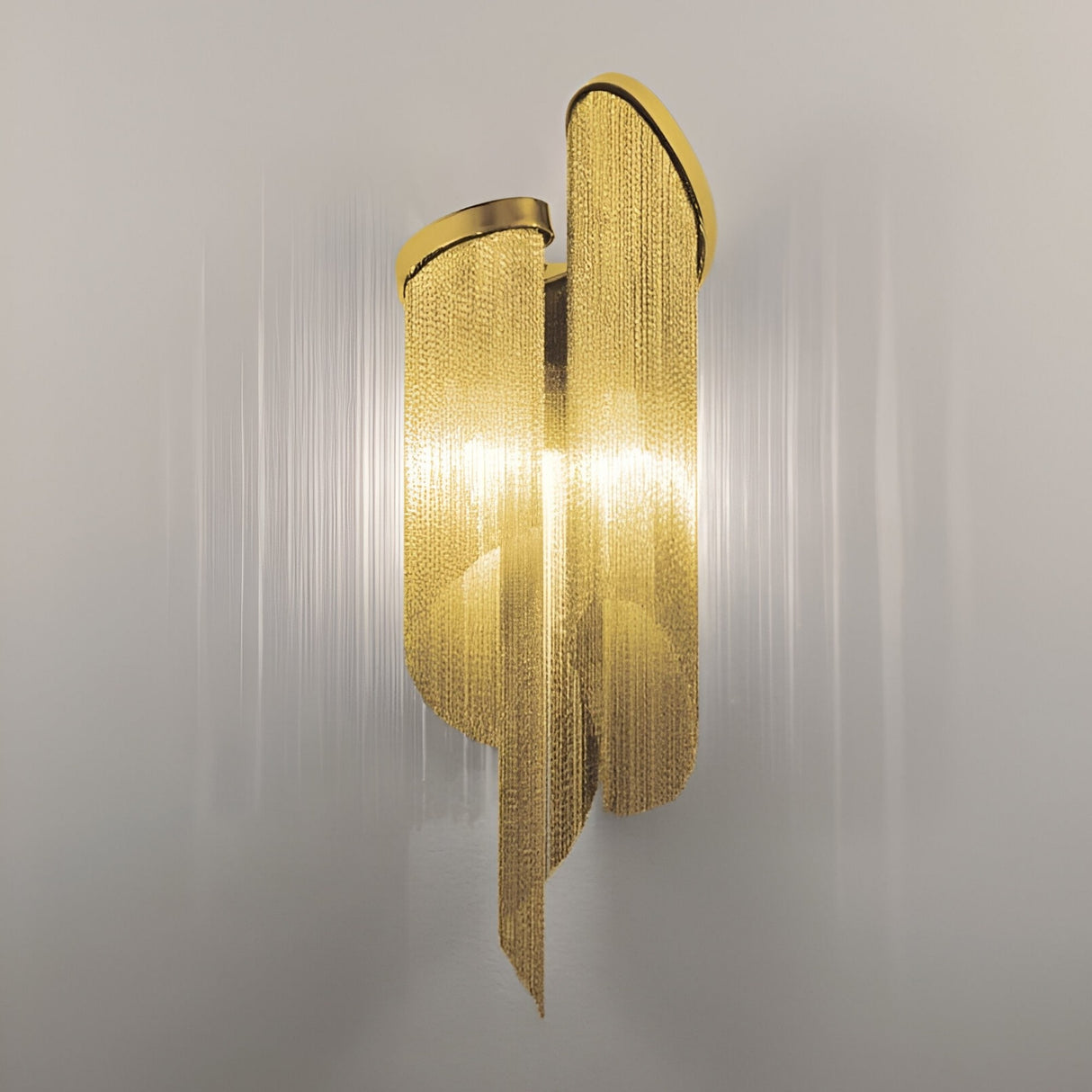 The Valora 2 Light Metal Chain Veil Wall Light in gold features cascading chains forming elegant curves. Its luxurious design glows softly, filtering light through the chains to cast subtle shadows and enhance any space with sophistication.