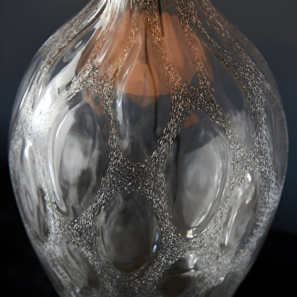 Close-up of Endon Brenstead table lamp base showing textured artisan glass with charcoal tint and matt antique brass detailing at the neck.