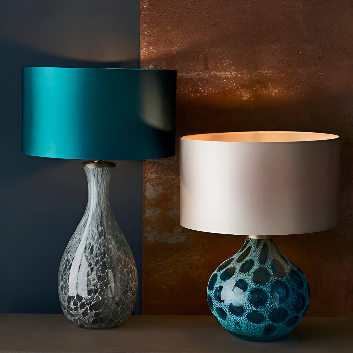 Carldale Table Lamp in Bronze with grey cloud-effect glass hourglass base, teal drum shade, shown beside a matching lamp with patterned blue base.
