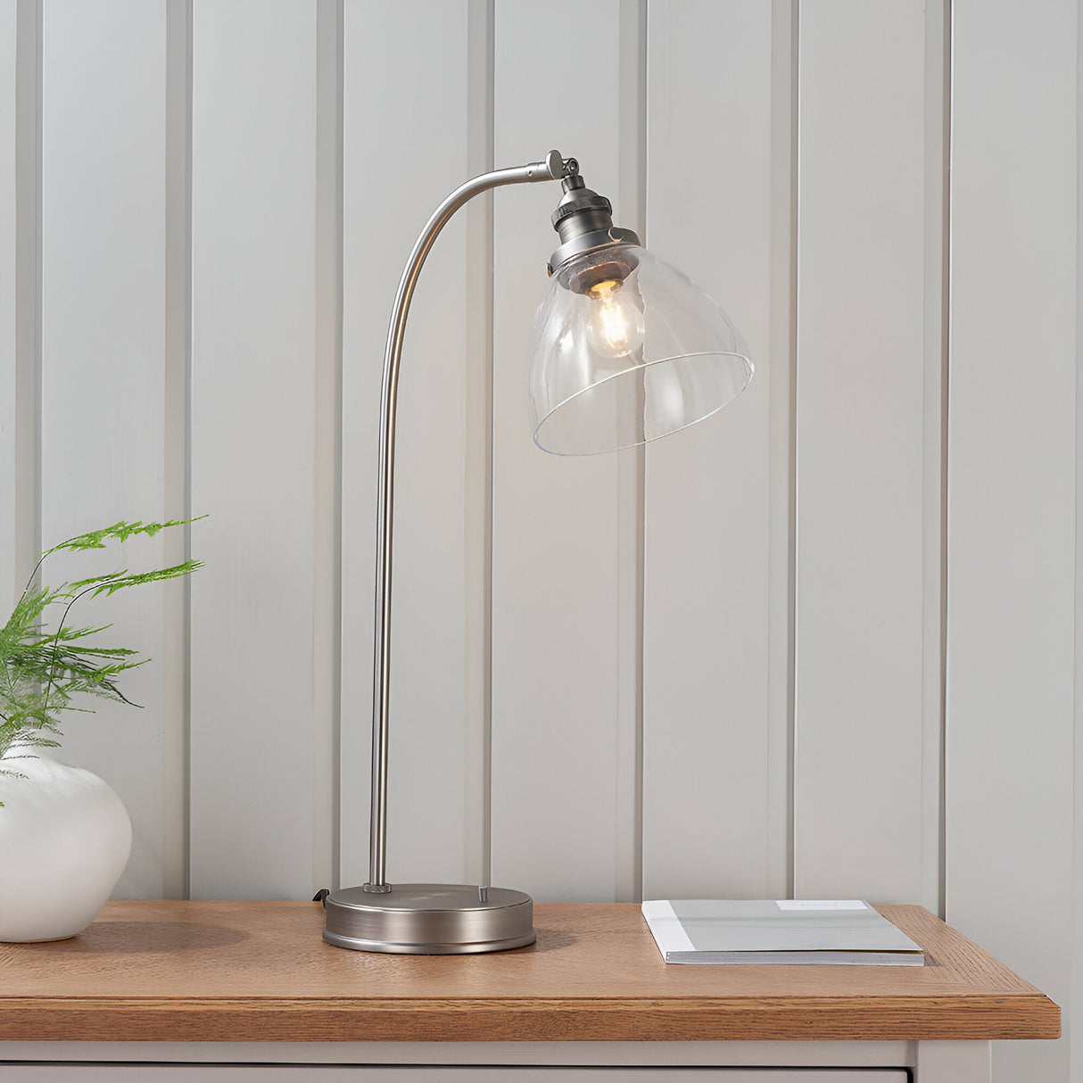 Endon Wentworth table lamp in brushed silver with arched stem, adjustable clear glass dome shade and knurled holder, styled on a wooden console.