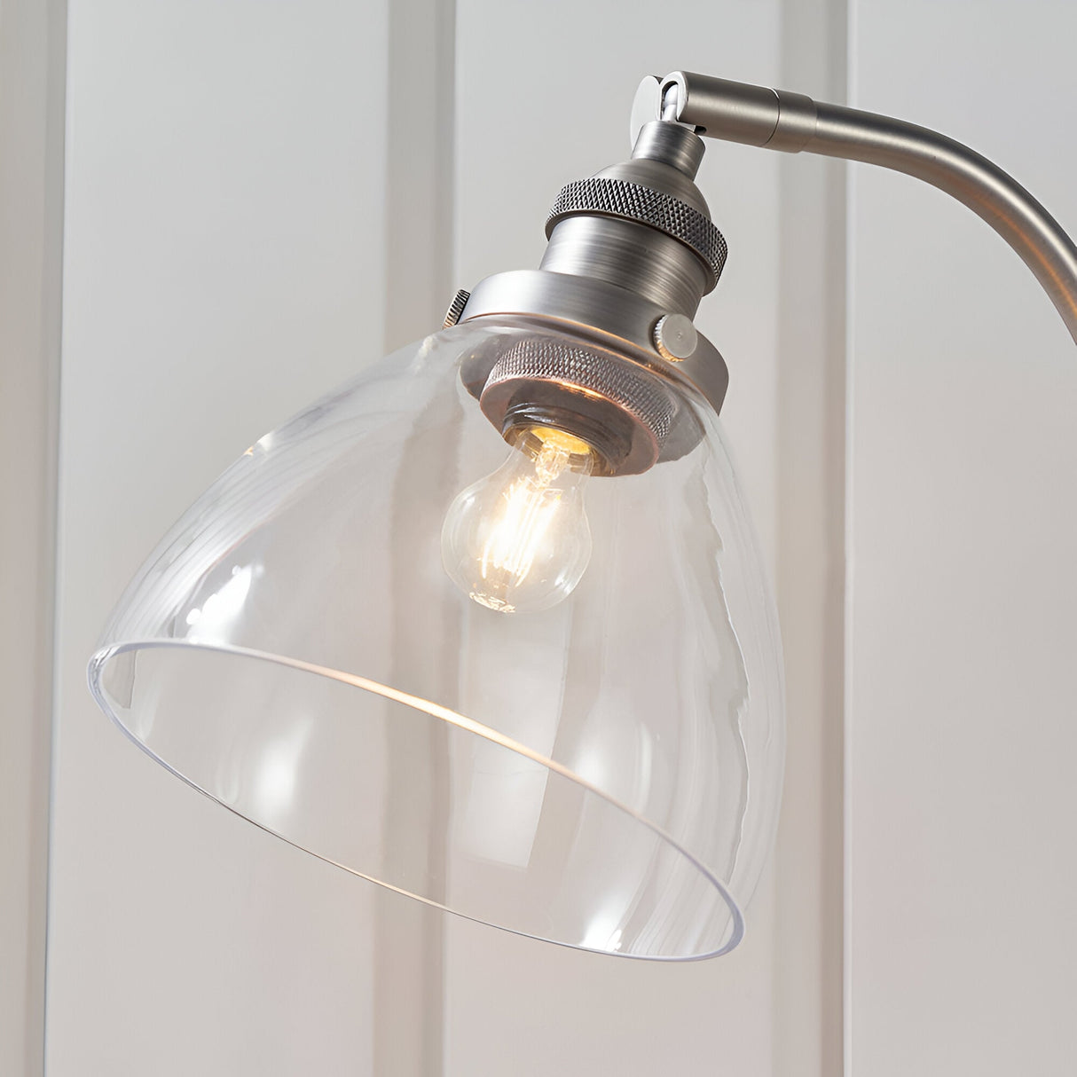 Close-up of the Endon Wentworth table lamp's clear glass dome shade, brushed silver knurled lamp holder, adjustable knuckle, and exposed E14 filament bulb.