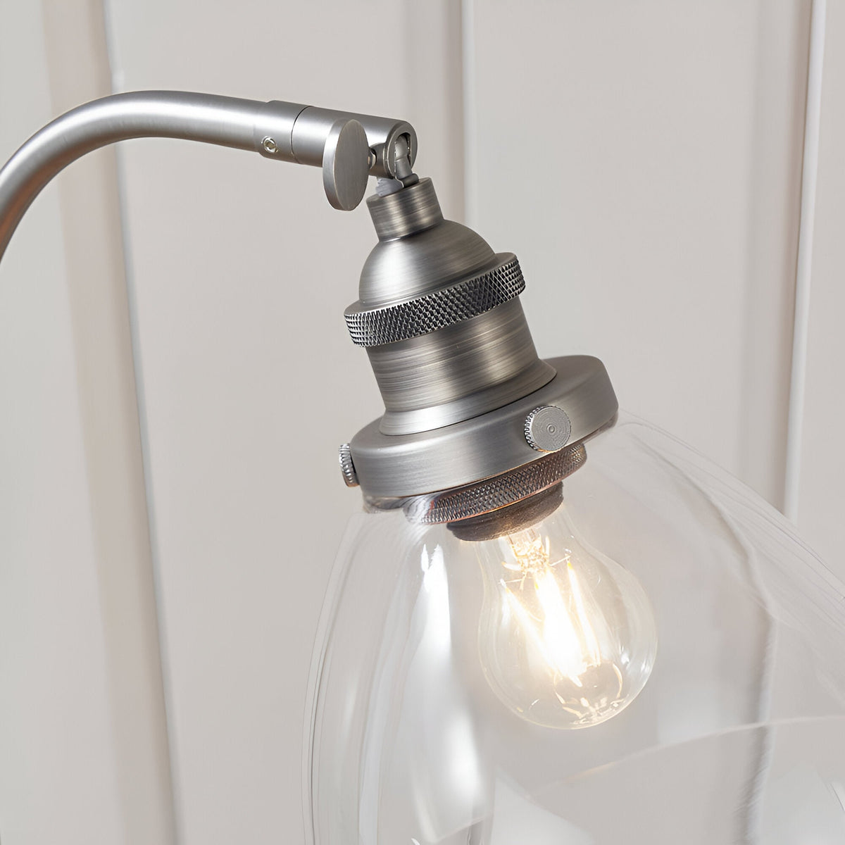 Close-up of the Endon Wentworth table lamp's brushed silver head with knurled holder, adjustable knuckle, clear glass shade and filament bulb.