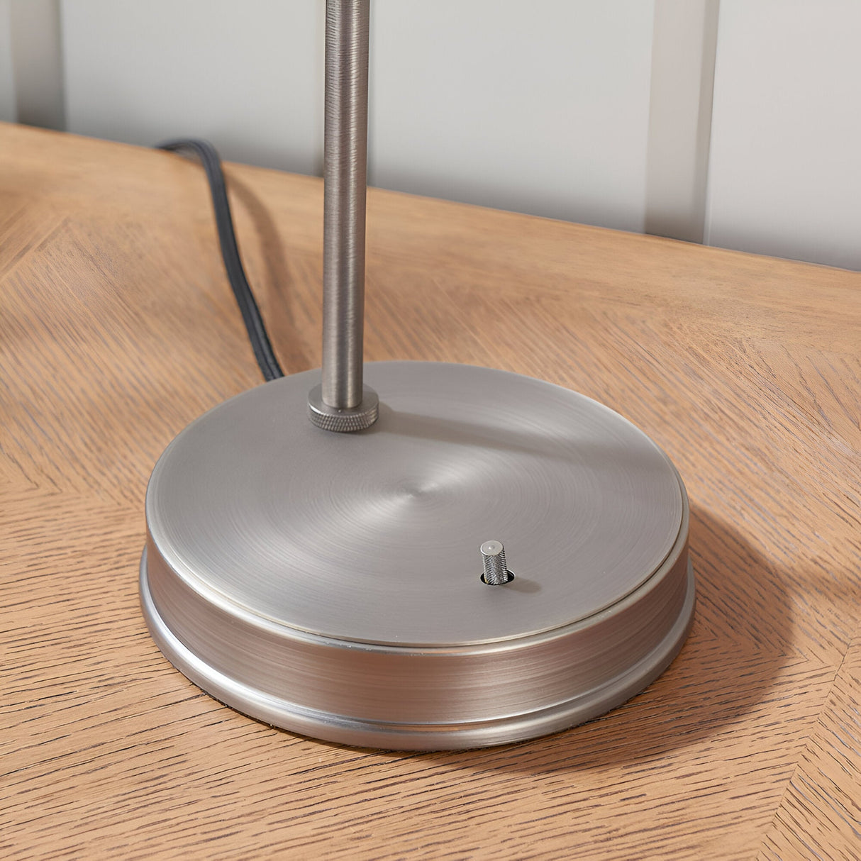 Close-up of the Endon Wentworth table lamp's round brushed silver base with knurled fitting detail, shown on a wooden surface.