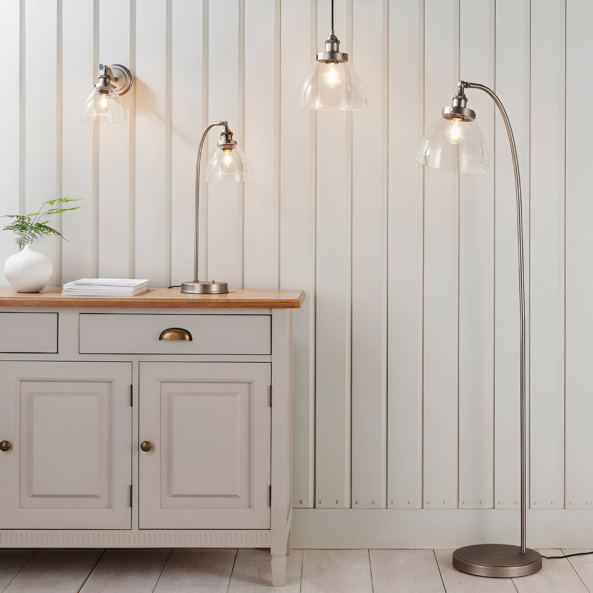 Endon Wentworth silver floor lamp with arched stem and clear glass shade, shown beside a cream sideboard with matching wall light, table lamp and pendant.