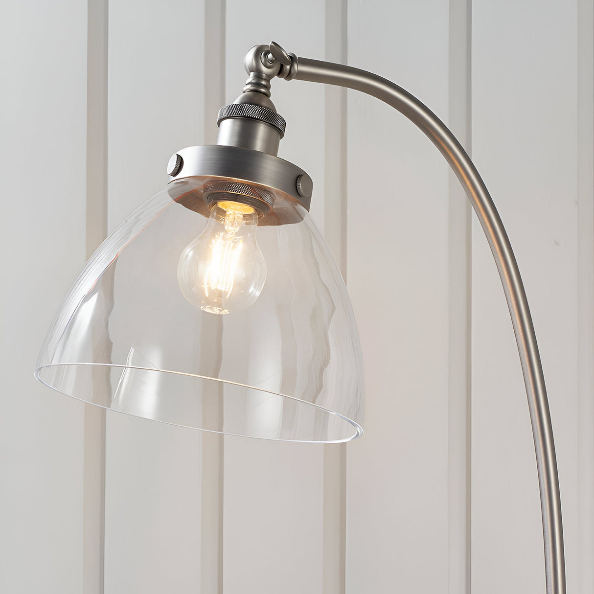 Endon Wentworth floor lamp in brushed silver with curved arm, knurled lamp holder and clear glass dome shade housing a visible E27 filament bulb.