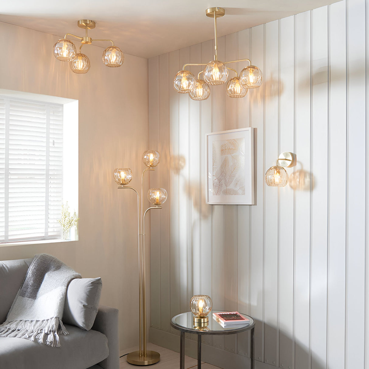 Endon Draycott wall light with champagne dimpled glass shade on satin brass arm, shown with matching pendant, floor and table lamps in a living room.