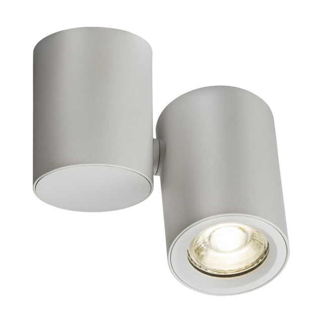 The Dee Single Round Spotlight - White is a contemporary cylindrical ceiling light fixture in a matte white finish. It offers dimmable options and comprises two sections: one enclosed and the other open, showcasing a GU10 light source that emits a bright spotlight.