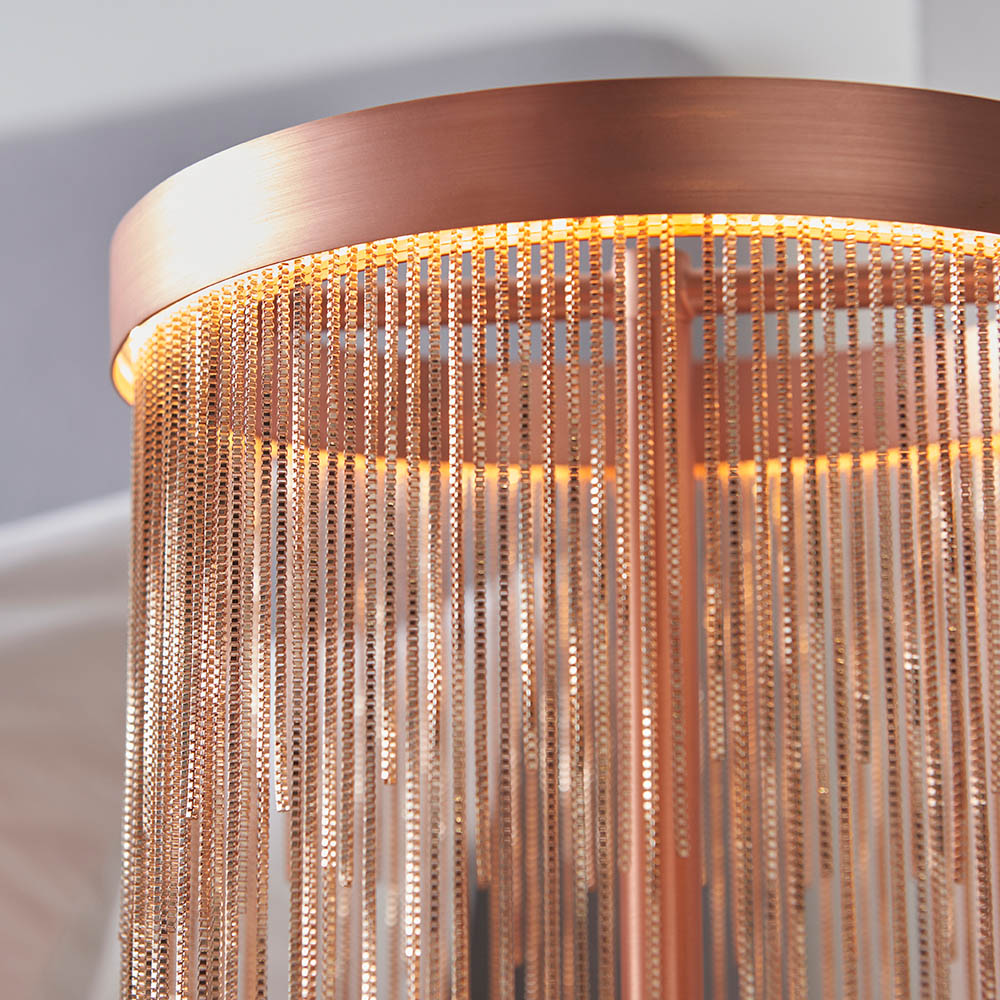 Close-up of the Endon Danestead table lamp showing its brushed copper LED ring and fine copper toned chains hanging at varied lengths, softly lit.