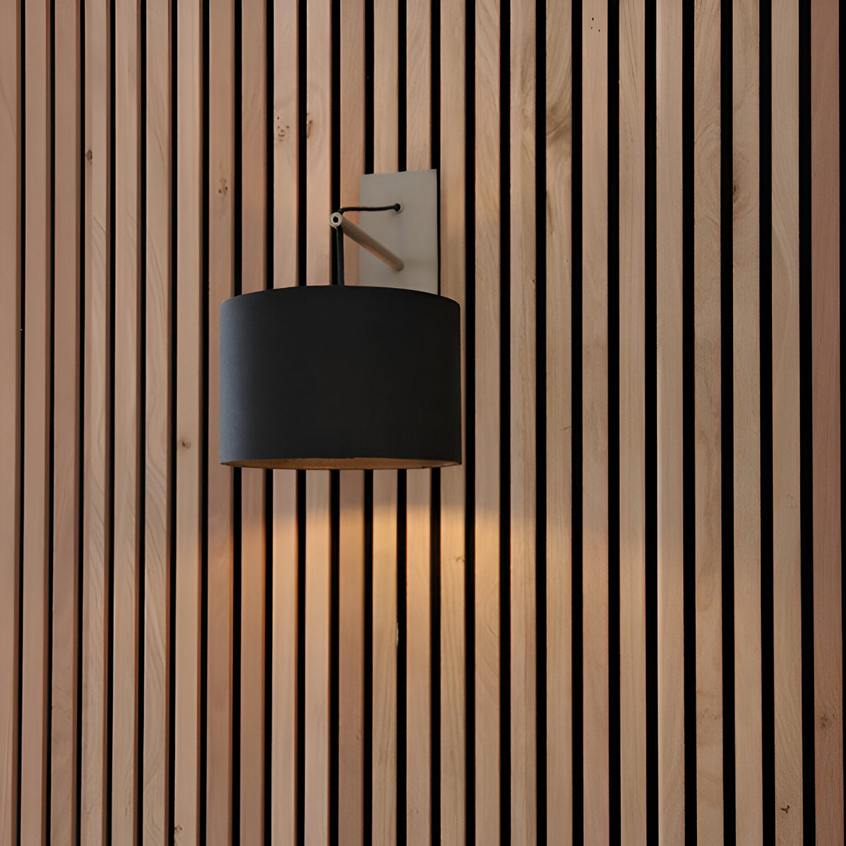 Carlfield Wall Light in nickel with a black rectangular base, cantilevered stem, and black fabric drum shade, mounted on a wood slat wall.