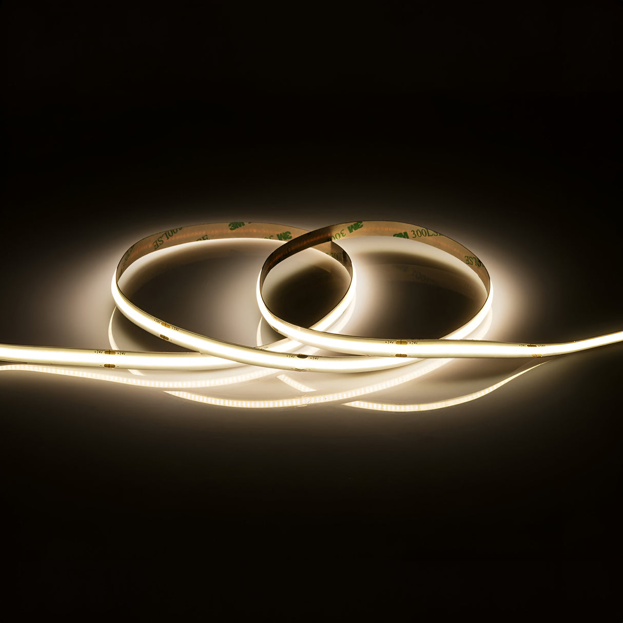 The 24V 11W COB LED Strip Light 5m - 4000K is arranged in a looped, coiled pattern on a reflective surface against a dark background, emitting a soft, warm glow.