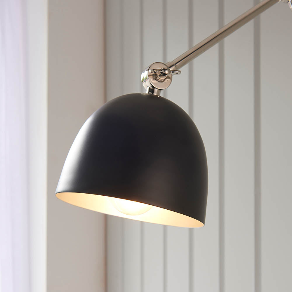 Endon Caldhurst wall light with polished nickel adjustable arm and matt black domed shade with painted inner, mounted against pale grey panelling.