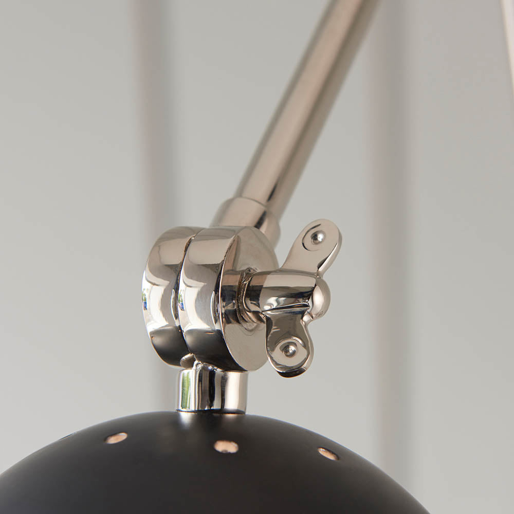 Close-up of the Endon Caldhurst wall light's polished nickel adjustable joint with knurled detail, above the matt black shade.