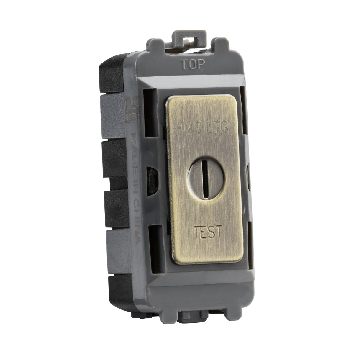 Close-up of a rectangular, dark gray electrical switch labeled as the 20AX DP Key Module (Marked EMG LTG TEST) with an antique brass faceplate from the Knightsbridge Grid System. The plate features a vertical slot in the center with "TEST" and "EMG LTG" engraved, and the top is labeled "TOP.