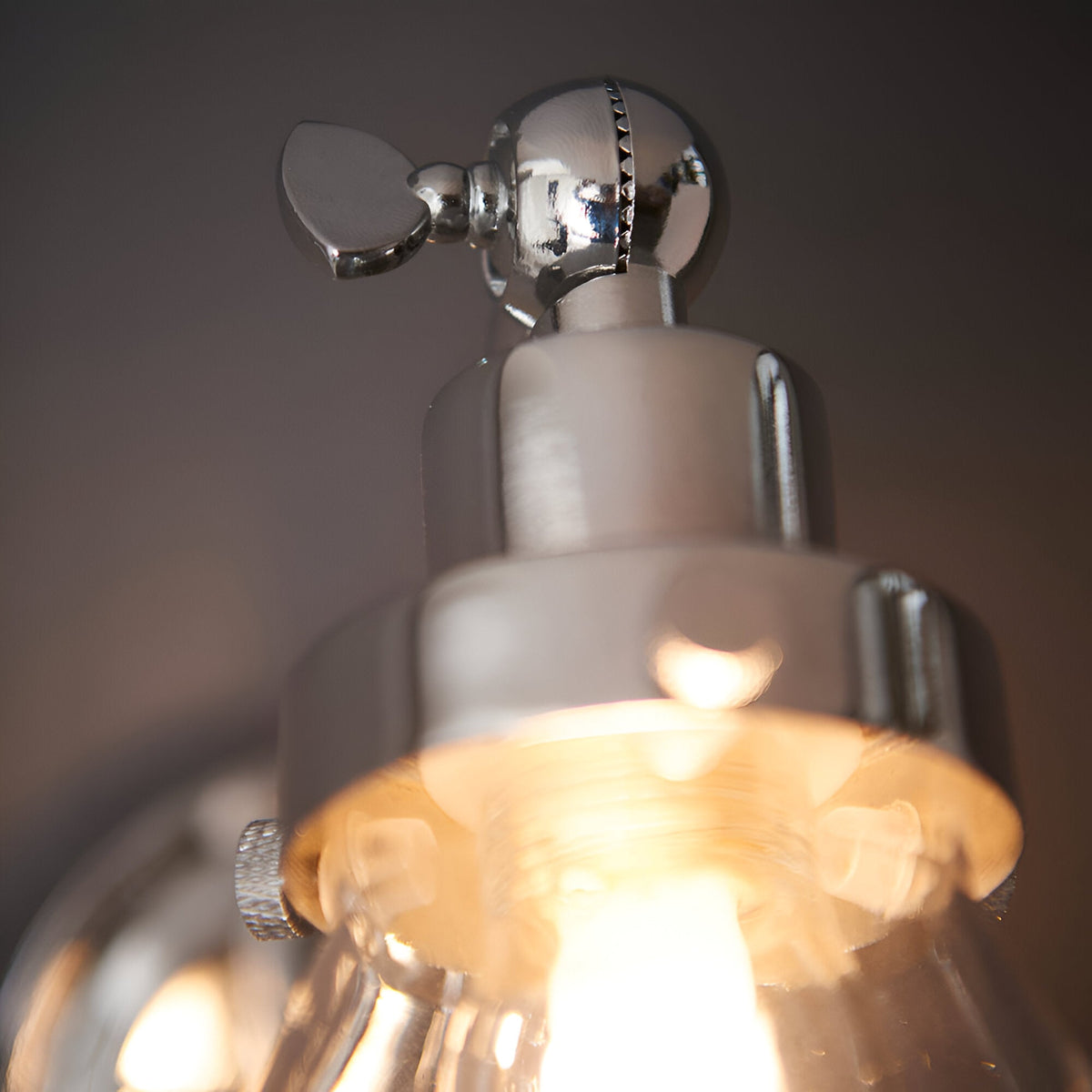 Close-up of the Endon Brackwood bathroom wall light in chrome, showing the adjustable head, pull cord fitting, and illuminated clear glass shade.