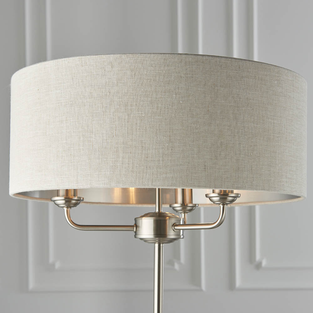 Close-up of the Brenley 3 Light Floor Lamp in brushed chrome, showing three E14 fittings beneath a natural linen drum shade with reflective inner lining.