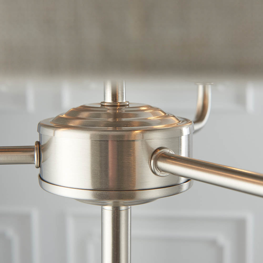 Close-up of the Brenley 3 Light Floor Lamp's brushed chrome hub, showing three angled metal arms and central stem joints.