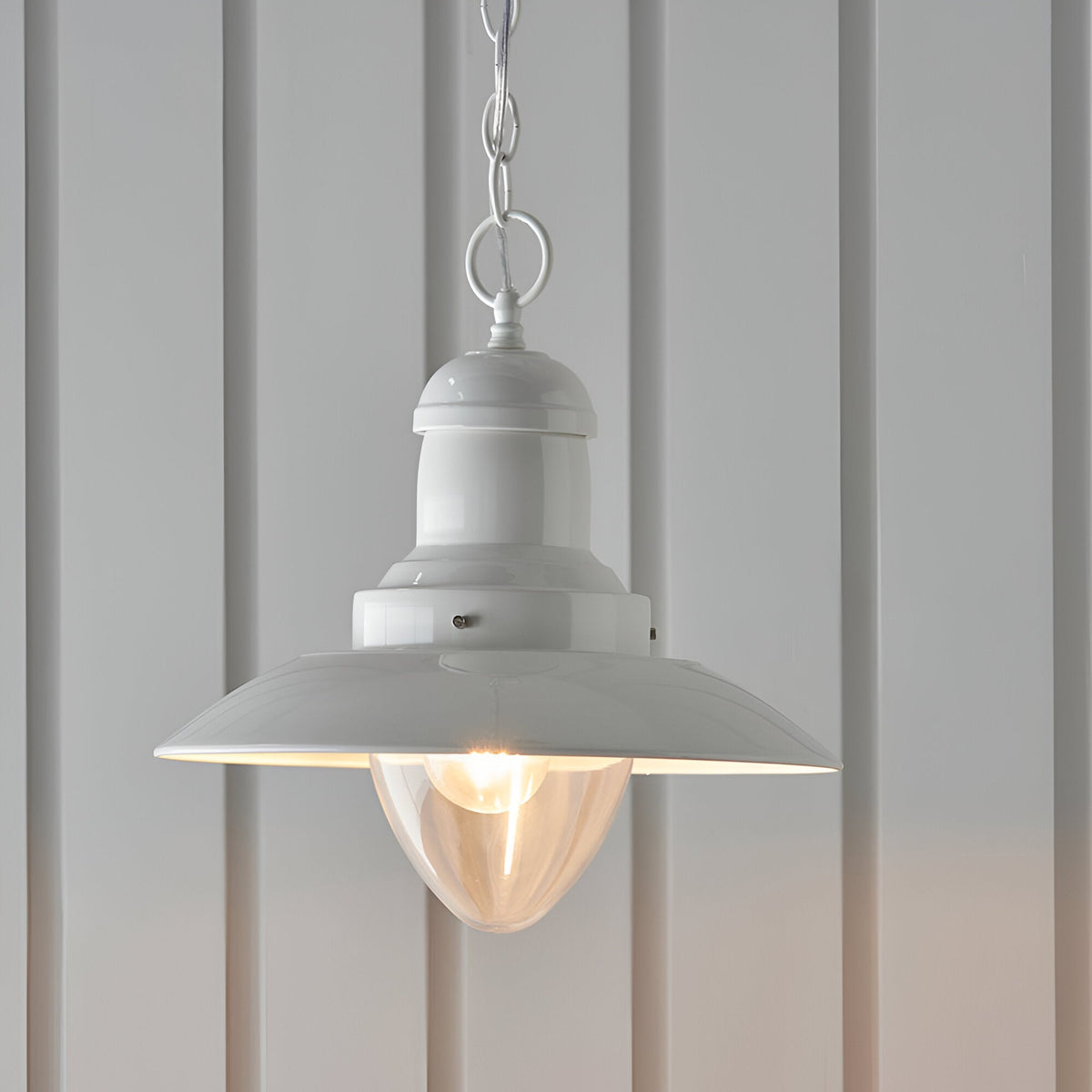 Endon Chartford cream gloss pendant light with shaped clear glass shade and chain suspension, hanging against pale panelled walls.