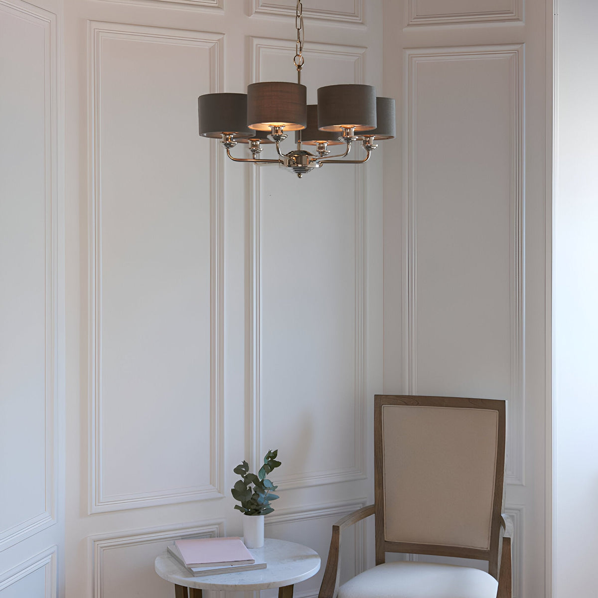 Endon Brenley V3 six-light pendant in nickel with charcoal drum shades, hanging from a chain in a panelled room above a marble side table and chair.