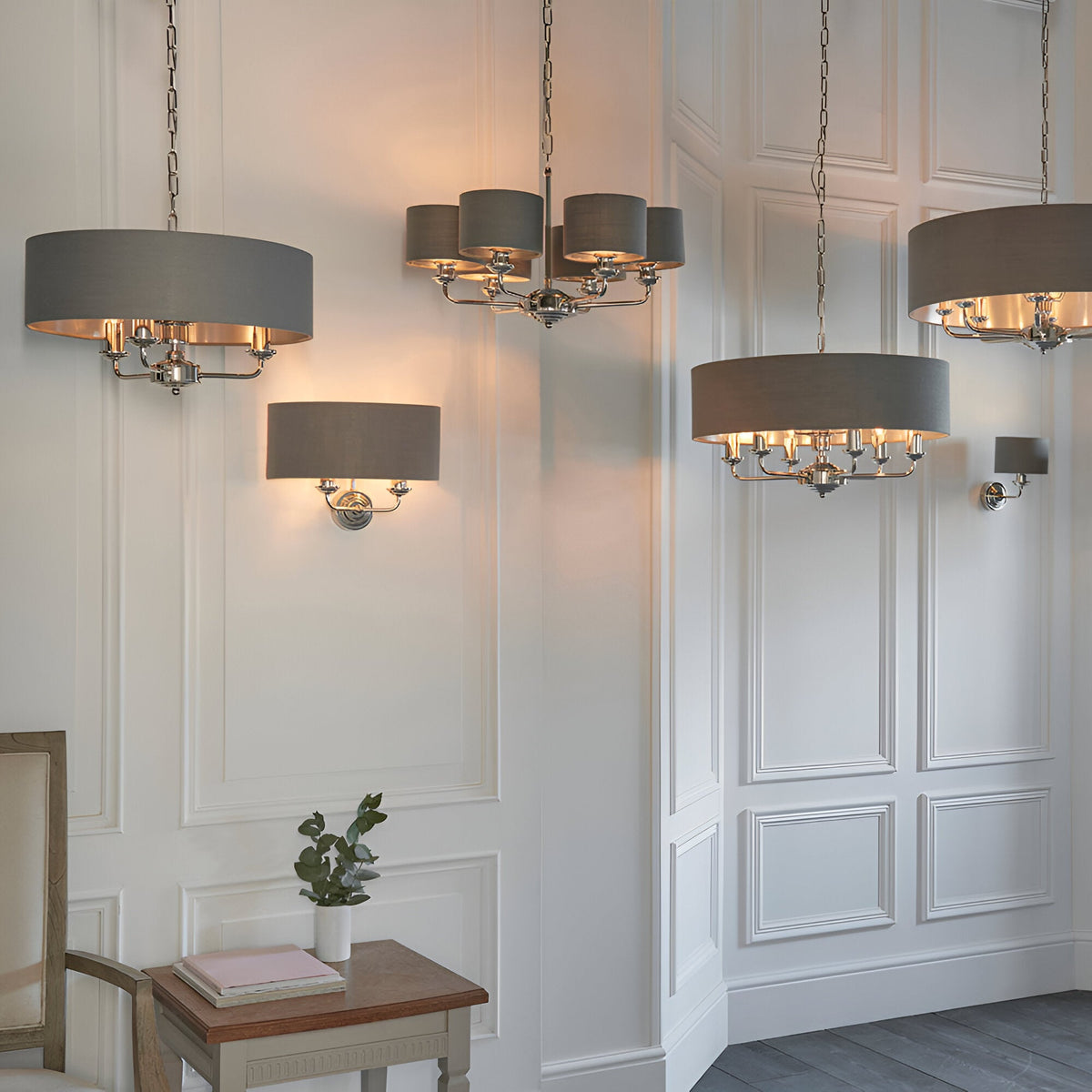 Endon Brenley V3 six-light pendant with grey drum shades and nickel chrome fittings, shown with matching chandeliers and wall lights on panelled walls.