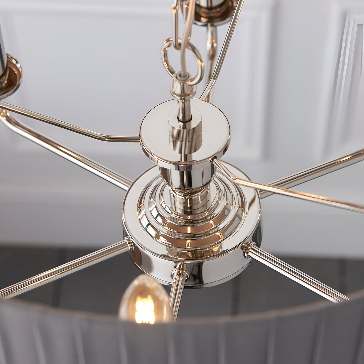 Close-up of the Brenley V1 6 light pendant's nickel and chrome centre hub with radiating arms and chain suspension, above a grey fabric shade.