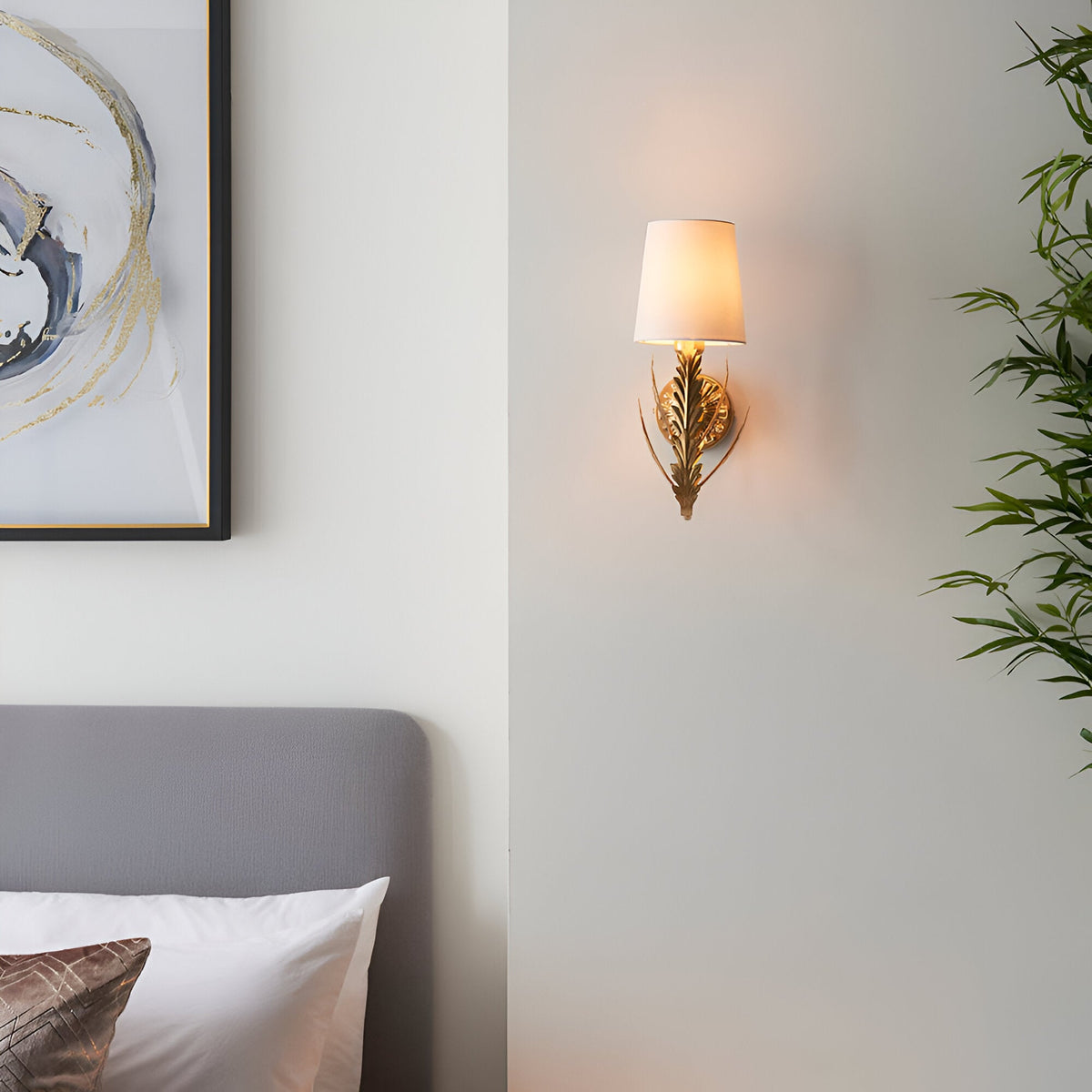 Colette Wall Light in gold leaf with layered leaf detail and cream fabric shade, mounted on a bedroom wall beside a framed artwork.