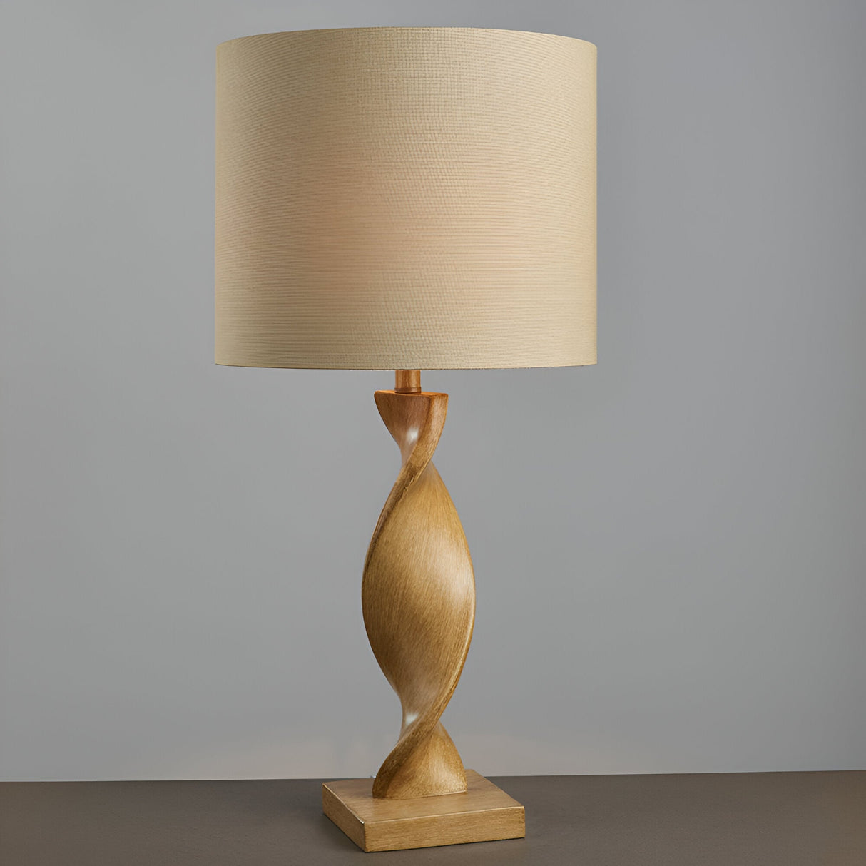 Alcott Table Lamp in natural finish, featuring a light oak-effect spiral wood base and a natural linen cylinder shade, set against a plain grey background.