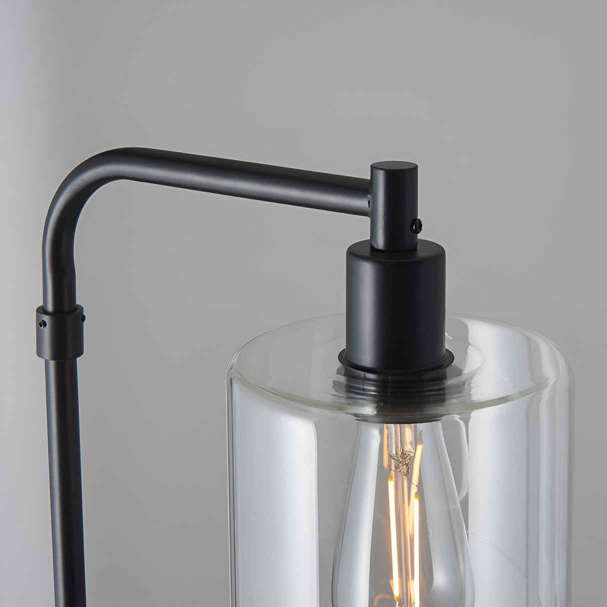 Close-up of the Cranmere Floor Lamp in matt black, showing the angled metal arm, E27 bulb holder, and clear glass shade with visible filament bulb.